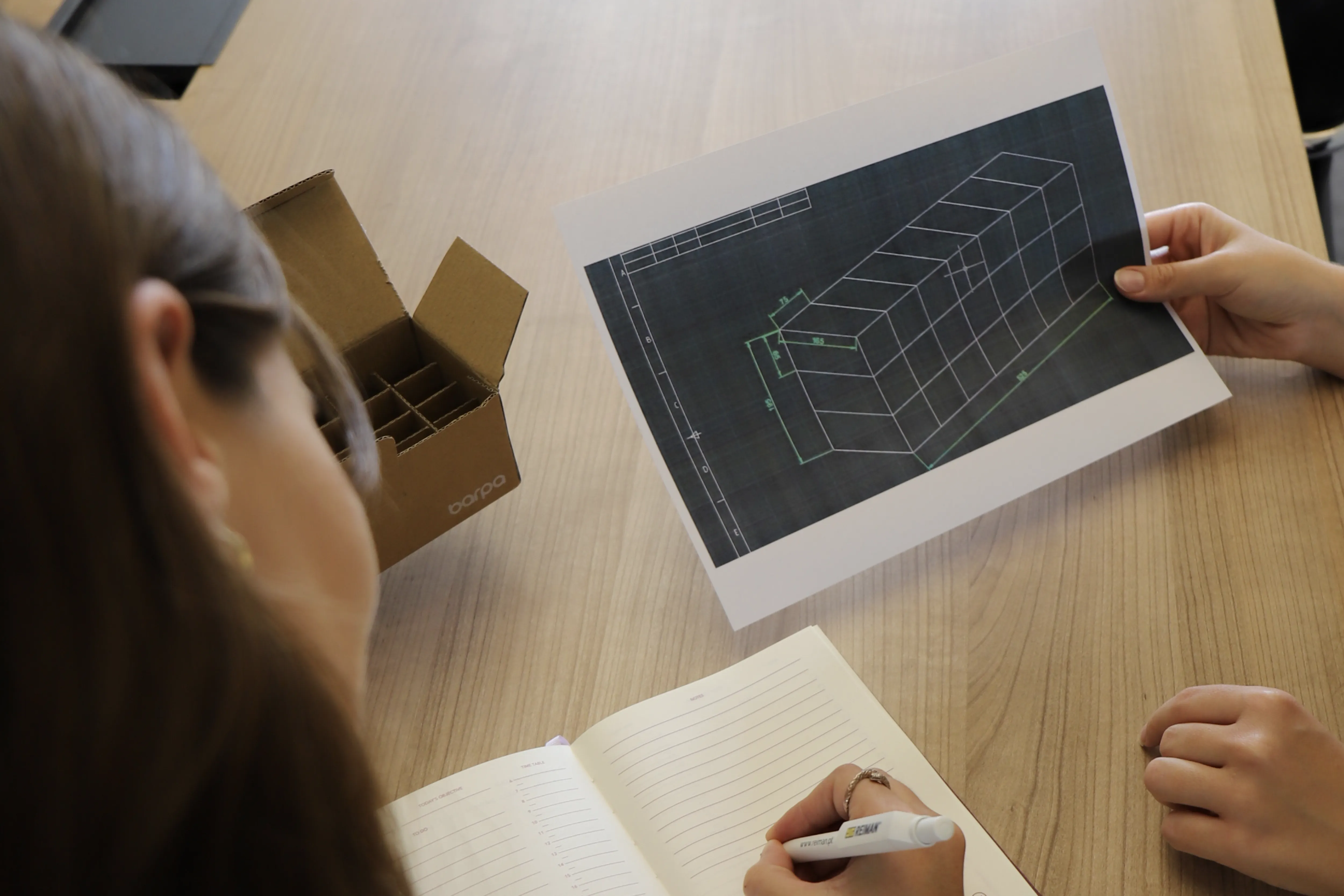 Person sketching a design from a blueprint.